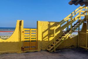 un escalier jaune à côté d'un mur jaune à côté de la plage dans l'établissement Casa BRISA DO MAR Abaís, à Praia Da Caueira