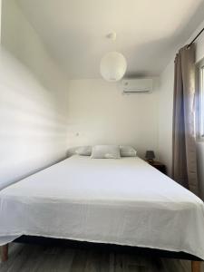 um quarto com uma cama branca e uma colcha branca em Âpara Feti'a - Mirimiri Lodge em Tevaitoa