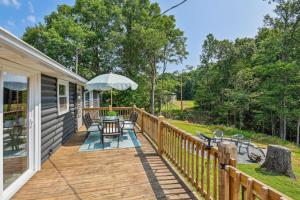 una terraza de madera con mesa y sombrilla en Peaceful White Bluff Vacation Rental with Pool!, en White Bluff