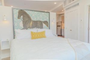 ein weißes Bett mit einem Bild eines Pferdes an der Wand in der Unterkunft The Hive Adjacent 1st Floor 101 pet 102 balcony Pet in Wilmington
