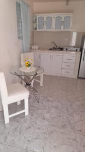 a kitchen with a glass table and a white chair at Residencial Lucy in Boca Chica +2 photos
