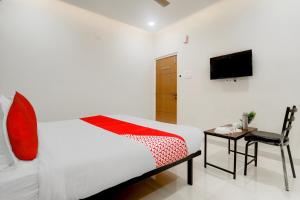 a bedroom with a bed and a chair and a television at Super Hotel O Prime Time Hotel in Hyderabad