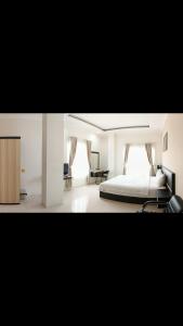 KHARIZ HOTEL في بوكيتينجى: غرفة نوم بيضاء مع سرير ومكتب