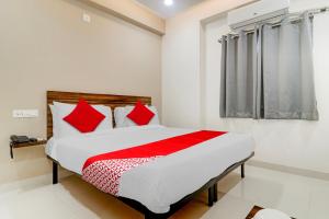 a bedroom with a bed with red pillows and a window at Super OYO Flagship Prime Time Hotel in Kukatpalli
