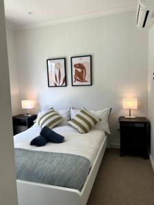a bedroom with a white bed with two lamps on it at Four-Bedroom Town House in Port Melbourne in Melbourne
