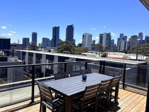 a wooden table on a balcony with a view of a city at Four-Bedroom Town House in Port Melbourne in Melbourne