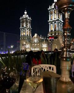 El Encanto في بوبلا: طاولة مع كوب من النبيذ ومبنى