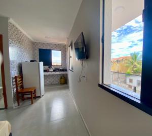 a kitchen with a white refrigerator and a window at Âncora Lofts in Arraial do Cabo