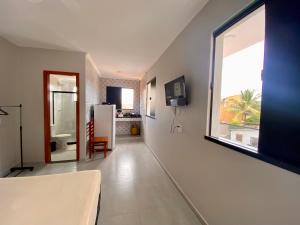 een woonkamer met een groot raam en een koelkast bij Âncora Lofts in Arraial do Cabo