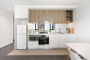 een keuken met witte kasten en een witte koelkast bij 2 Bedroom Apartment in Southbanks Stature Building in Melbourne