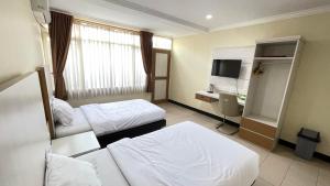 ein Hotelzimmer mit 2 Betten und einem Waschbecken in der Unterkunft tekMIRA Hotel in Bandung