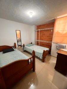 Catia La MarにあるApartamento Aeropuerto Maiquetia en Planta Bajaのレンガの壁、ベッド2台が備わるベッドルーム1室が備わります。