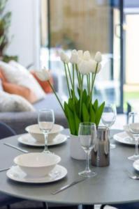 een tafel met borden, glazen en bloemen erop bij Central City Awaits 2 bed 2 bath with carpark in Christchurch