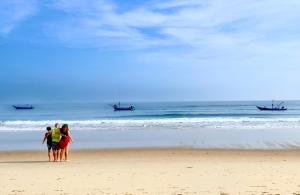 three people standing on a beach looking at the ocean at Wyndham Garden Hoi An Cua Dai Beach in Hoi An