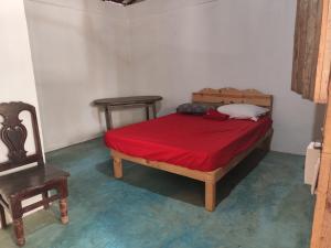 a bedroom with a bed with a red blanket and a chair at Posada Piedra de Fuego in Zipolite