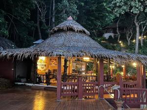 a restaurant with a straw hut with tables and chairs at Koh Jum Resort in Ko Jum
