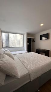 a bedroom with a large white bed with a window at HOSTELFC CORFERIAS in Bogotá