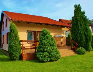 a house with a porch with a bench and trees at Holiday Home Kubus in Poddąbie