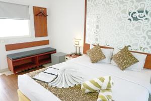 a bedroom with a white bed with a bench and a window at Samsara Inn in Legian