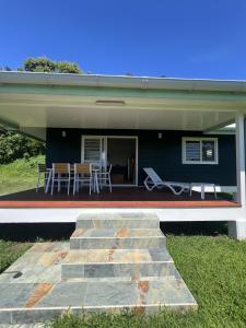 ein blaues Haus mit einer Terrasse, einem Tisch und Stühlen in der Unterkunft Painapoo - Mirimiri Lodge in Tevaitoa