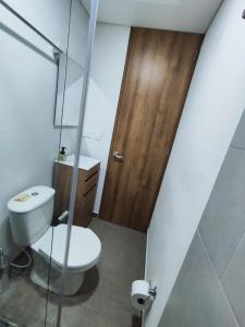 a bathroom with a toilet and a wooden door at Apartamento 202 in Guatavita