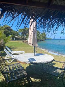 Vaiana Home 2 - bord de lagon في Taputapuapea: طاولة وكراسي مع مظلة والمحيط