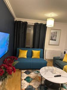 Entire flat in Ealing في لندن: غرفة معيشة مع أريكة زرقاء وطاولة