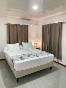 Cette chambre comprend un grand lit et des rideaux. dans l'établissement Vaiana Home 1, à Taputapuapea