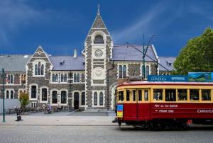 un autobús delante de un edificio con una torre de reloj en Central City Awaits 2 bed 2 bath with carpark en Christchurch