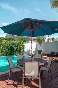 Casa de Temporada Homer House في بورتو سيغورو: طاولة وكراسي مع مظلة بجوار حمام السباحة