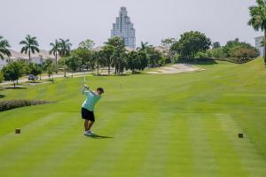 a woman swinging a golf club on a golf course at Beach villa with cozy terrace in Río Hato