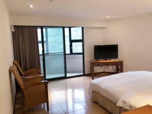 a bedroom with a bed and a television and a chair at King's Resort & Spa in Taian