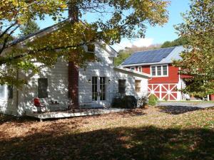 a white house with a red barn with solar panels at the farmhouse suite at gallatin farmstead in Red Hook