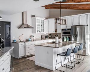 a kitchen with white cabinets and a island with bar stools at Great Location, 10 Mins to Beach, Vero Pool House in Vero Beach