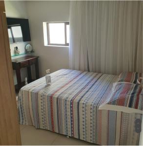 um quarto com uma cama com um cobertor listrado em Engenho da Praia em Porto de Galinhas