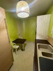 eine grüne Küche mit einem Tisch und einem Waschbecken in der Unterkunft Appartement JO 2024 Paris Disney in Villeparisis
