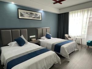 张家界喜见客栈 في تشانغجياجيه: سريرين في غرفة فندق بجدران زرقاء