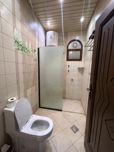 a small bathroom with a toilet and a shower at Friday Suites in Al-ʿUla