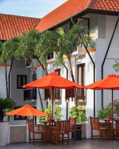 un groupe de tables avec parasols orange devant un bâtiment dans l'établissement HARRIS Hotel Kuta Tuban Bali, à Kuta