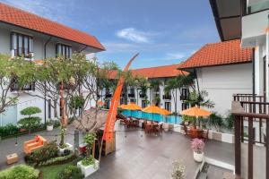クタにあるHARRIS Hotel Kuta Tuban Baliのテーブル、椅子、パラソルのある屋外の中庭