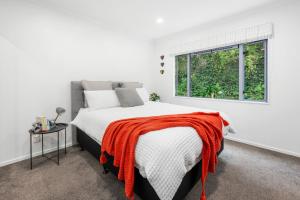 a bedroom with a bed with a red blanket on it at Hillcrest Hideaway - Napier Holiday Apartment in Napier