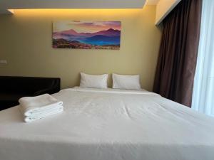 Un dormitorio con una cama blanca con toallas. en QUINCE HOME GRAND ION DELEMEN GENTING HIGHLANDs, en Genting Highlands