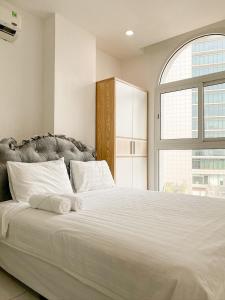 a bedroom with a large white bed with a window at Aloha House Apartment in Ho Chi Minh City