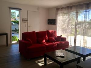 a living room with a red couch and a table at Maison Famille 8 pers, Jardin et Terrasse à Jard-sur-Mer - FR-1-336-104 in Jard-sur-Mer