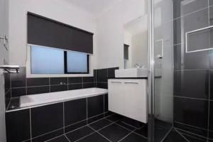 a black and white bathroom with a sink and a shower at Mel south east huge luxury home in Keysborough