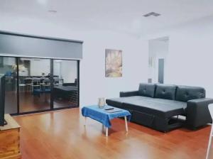 a living room with a black couch and a table at Mel south east huge luxury home in Keysborough