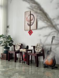 a room with two chairs and a guitar on the wall at The Hygge House in Da Nang