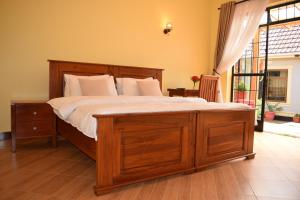Un dormitorio con una gran cama de madera con almohadas blancas. en Tongas place, en Arusha