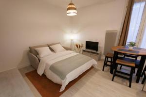 ein Schlafzimmer mit einem Bett und einem Tisch und einem Fernseher in der Unterkunft Lafra 2 - Chaleureux & Intime - Mon Groom in Troyes