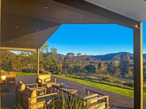 a deck with tables and chairs and a view of the mountains at Pindara in Broke